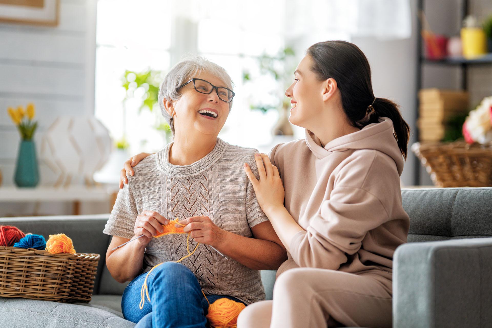 Alltagshelferin mit einer Seniorin auf dem Sofa
